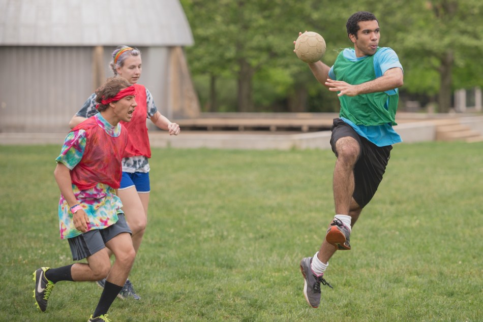 A student holding a ball about to jump and throw it.